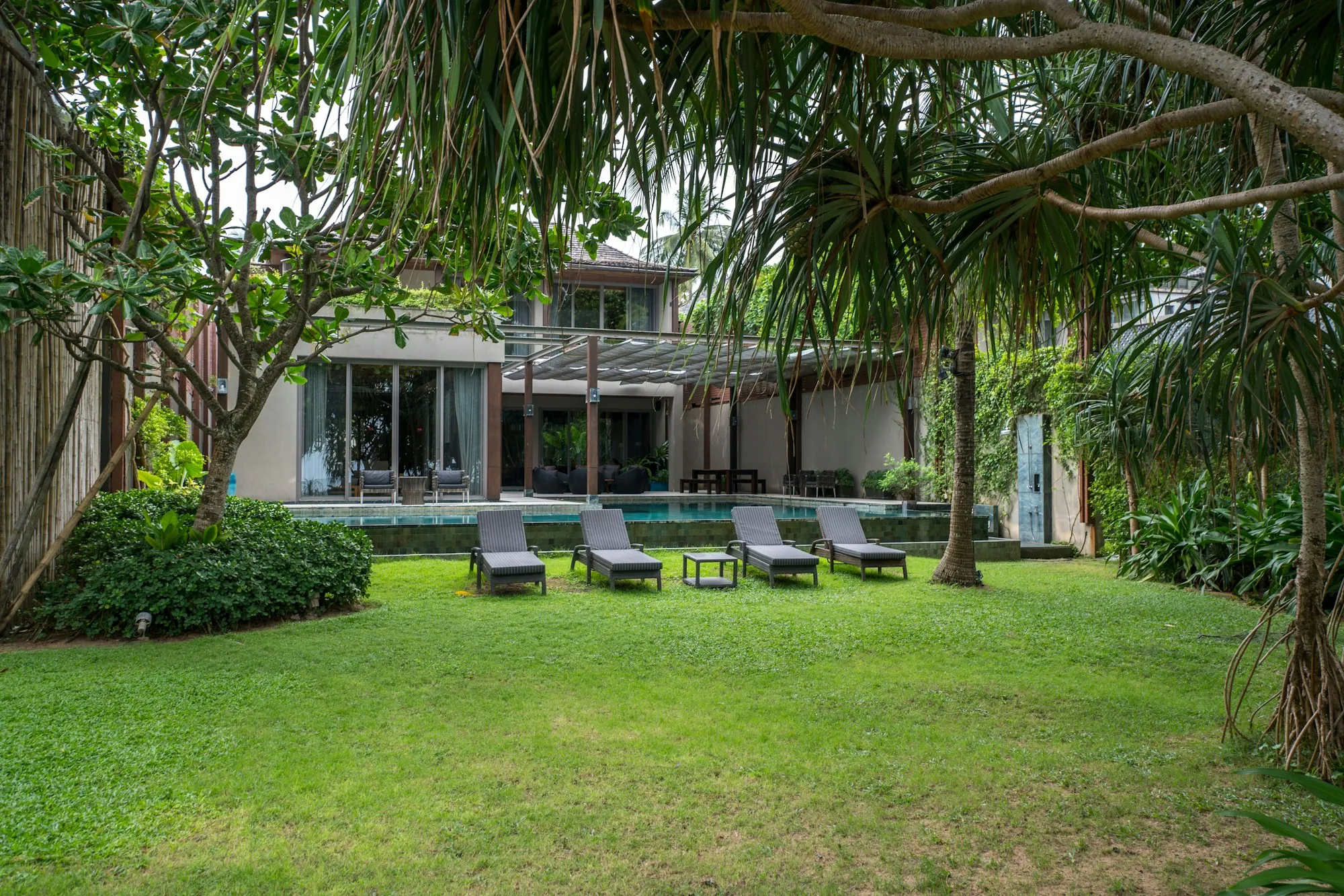 Rumah Flamboyan seen across the lawn, loungers by the pool