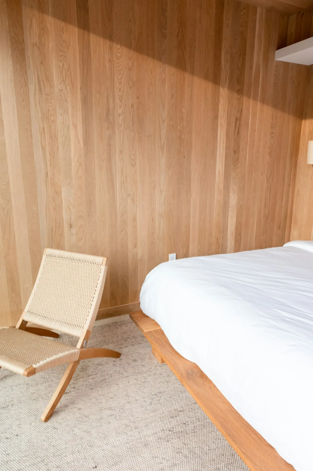 Bedroom at Rumah Pasir with oak panelling and a woven chair